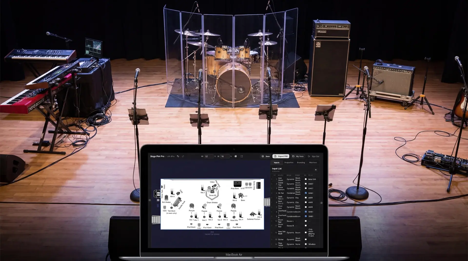 Stage Plot Pro on a laptop sitting on a real stage with drum kit, mic stands, keyboards, and amplifiers