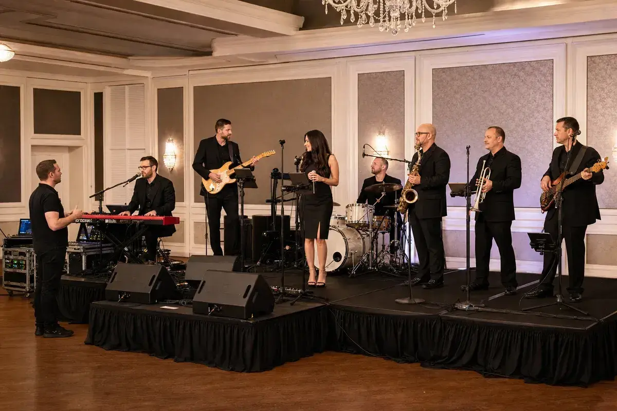 Eight-piece wedding band and technician completing soundcheck in a ballroom
