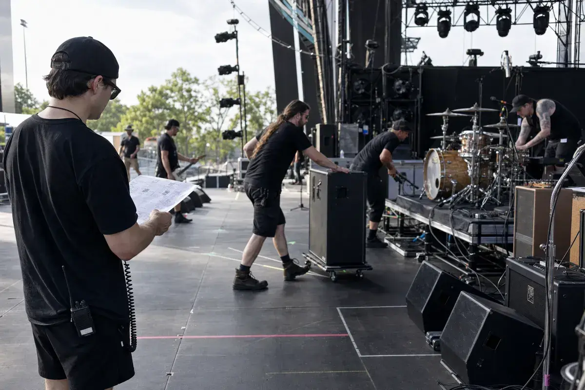 Festival crew completing an organized stage changeover while checking the production advance